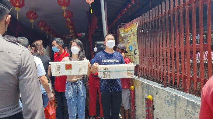 Rudi (baju biru) dan Cindy sedang memegang keranjang berisi burung pipit yang akan diterbangkan di depan Vihara Dharma Bhakti, Glodok, Jakarta Barat pada Selasa (1/2/2022).