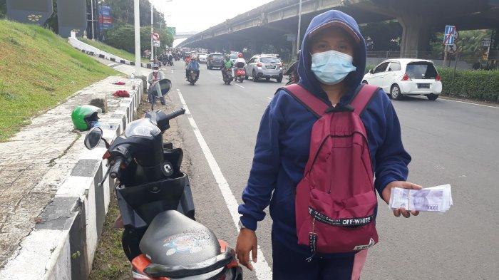 Serli (37) sedang memegang uang pecahan baru di tepi Jalan TB Simatupang, Cilandak Barat, Cilandak, Jakarta Selatan pada Selasa (11/5/2021).