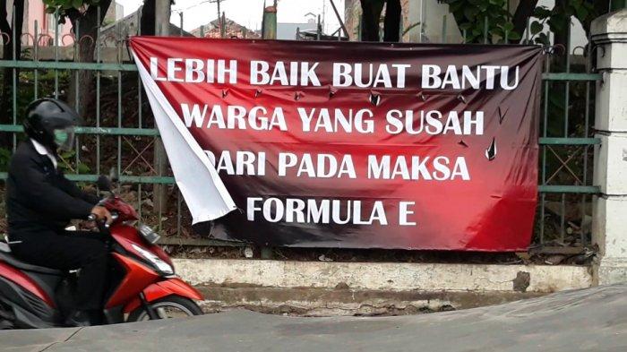 Spanduk bernada penolakan kegiatan Formula E yang dipasang di pagar pembatas Jalan Raya Bogor, Jakarta Timur, Senin (6/9/2021).