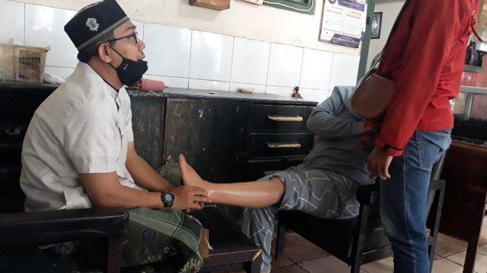 Seorang wanita (kerudung abu-abu) menahan sakit saat kaki kirinya diurut di pengobatan alternatif Haji Naim pada Rabu (17/3/2021).
