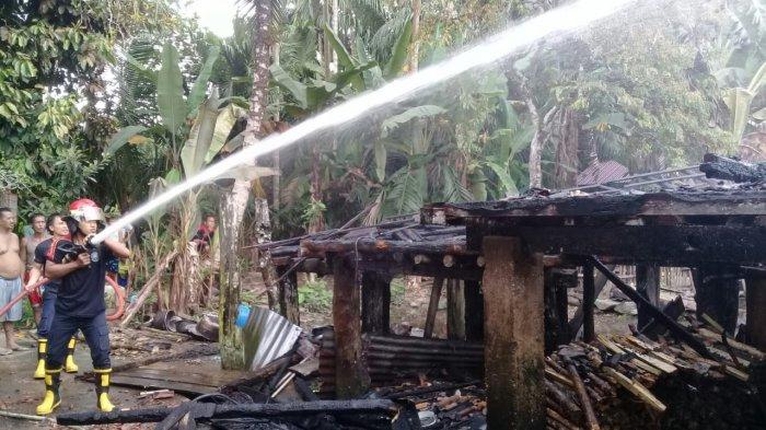 Petugas memadamkan api yang membakar rumah panggung milik Ramzi