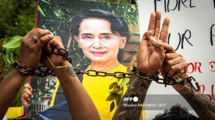 Para migran Myanmar di Thailand menunjukkan salam tiga jari dan foto pemimpin sipil Myanmar Aung San Suu Kyi yang ditahan pada sebuah protes terhadap kudeta militer di negara asal mereka, di depan gedung ESCAP PBB di Bangkok pada 22 Februari 2021.