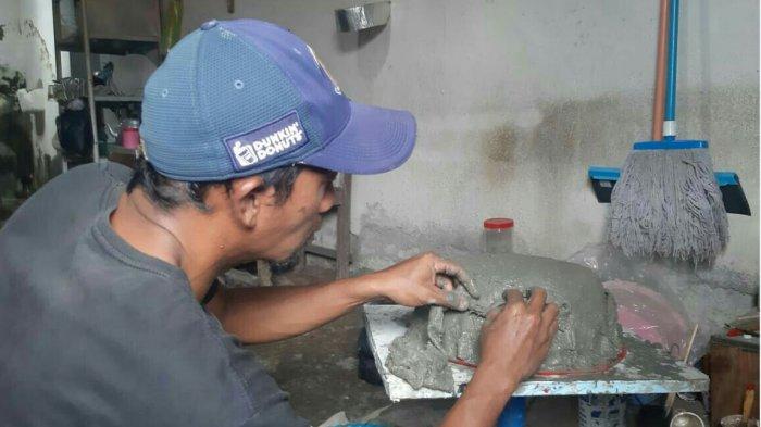 Kuswanto (44), warga Desa Tangkilan, Legok, RT 01/RW 04, Kecamatan Margasari, Kabupaten Tegal, saat menunjukkan salah satu hasil karyanya berupa pot bunga yang dibuat dengan memanfaatkan limbah handuk dan kain bekas sebagai bahan dasar. Kuswanto pun menunjukan bagaimana proses pembuatannya, Kamis (18/3/2021) kemarin.