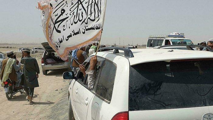 Orang-orang mengibarkan bendera Taliban saat mereka melewati kota perbatasan Pakistan, Chaman, pada 14 Juli 2021.