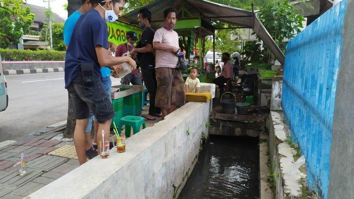 Para pelanggan angkringan Anugrah memberikan pakan kepada ikan di selokan di dekat angkringan tersebut di pinggir Jalan Jenderal Sudirman, Cabean, Semarang Barat,Kota Semarang, Selasa (1/12/2020).