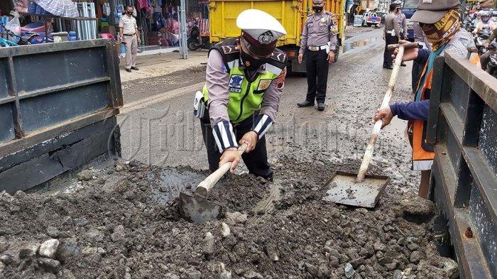 Anggota Satlantas Polres Pekalongan menambal jalan berlubang di depan Pasar Bojong.