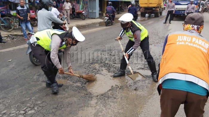 Anggota Satlantas Polres Pekalongan menambal jalan berlubang di depan Pasar Bojong.
