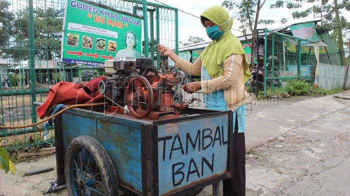 Sri Sutini (41) Ibu satu anak membuka jasa tambal ban akibat suaminya alami kebutaan sehingga tak lagi bisa bekerja di Jalan Tambak Dalam Raya, Gayamsari, Kota Semarang atau di sisi timur SPBU Masjid Agung Semarang, Senin (9/3/2021).