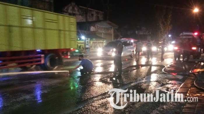 Petugas Damkar dibantu warga dan polisi membersihkan limbah mi instan yang berceceran di Jalan Daendels Lamongan, Jumat (24/12/2021).