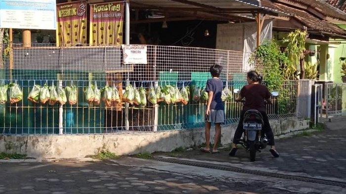 Warga tampak sedang mengambil sayuran gratis yang digantungkan di pagar rumah. Paket sayuran ini dibagikan oleh komunitas Sejangkauan Tangan yang merupakan gerakan sosial membantu warga dengan membagikan sayuran gratis di masa pandemi ini