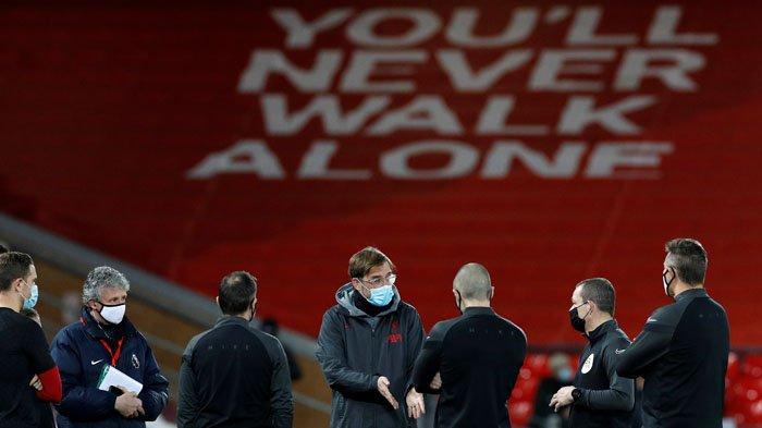 Manajer Liverpool Jurgen Klopp (tengah), mengenakan masker atau penutup wajah berbicara dengan para petugas menjelang pertandingan sepak bola Liga Premier Inggris antara Liverpool dan Brighton dan Hove Albion di Anfield di Liverpool, Kamis 4 Februari 2021.