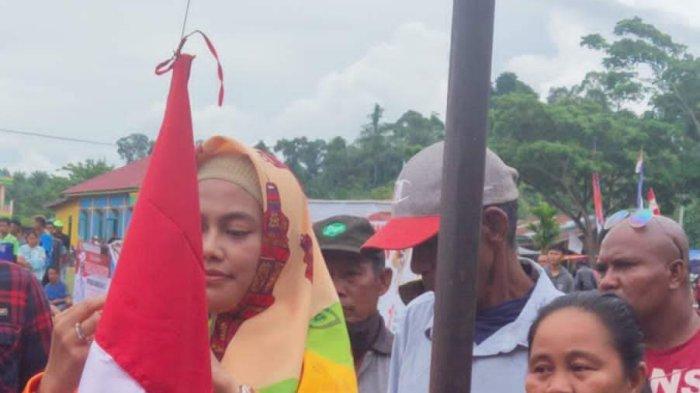 Bupati Nunukan Asmin Laura sedang mengikat bendera merah putih pada tiang bendera, di Kecamatan Tulin Onsoi, Minggu (30/07/2022).