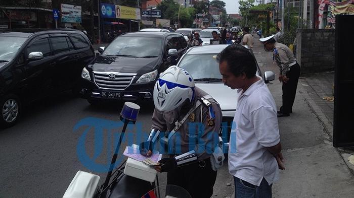 Seorang pengendara mobil mendapat peringatan dari polisi karena parkir di pinggir jalan Teuku Umar, Kamis (3/3/2016)
