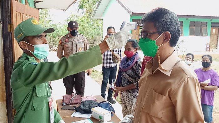 Petugas TPS PSU Sabu Raijua sedang mengecek suhu tubuh calon bupati nomor urut 01 Nikodemus Rihi Heke (kanan) saat hendak mencoblos di TPS 01 Desa Eilode, Kecamatan Sabu Tengah, Kabupaten Sabu Raijua, Rabu 7 Juli 2021 pagi.
