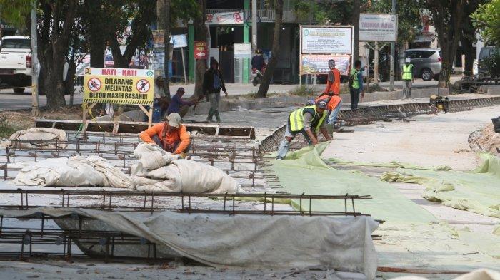 Sejumlah pekerja sedang menyelesaikan pembangunan rigid beton di Jalan Ryacudu, Kecamatan Sukarame, Bandar Lampung, Sabtu (31/7/2021).