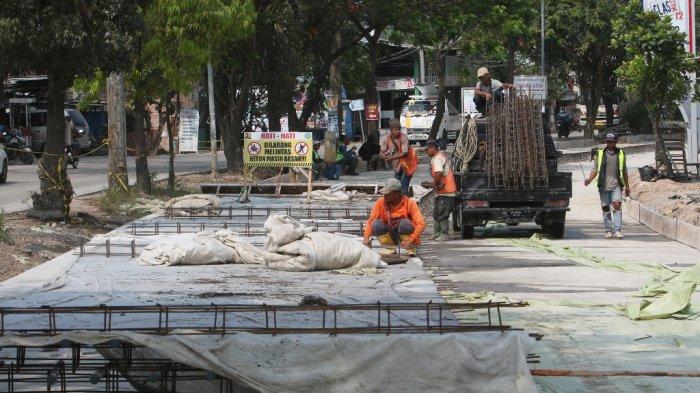 Sejumlah pekerja sedang menyelesaikan pembangunan rigid beton di Jalan Ryacudu, Kecamatan Sukarame, Bandar Lampung, Sabtu (31/7/2021).