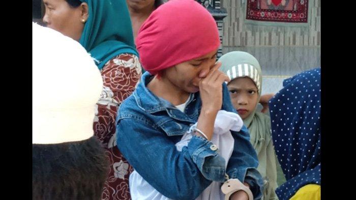 Pelaku (berkerudung merah) usai membunuh ayah kandungnya sendiri saat berada di kediamannya, Dusun Katedungan, Desa Pasarenan Kecamatan Kedungdung, Kabupaten Sampang, Madura, Rabu (18/5/2022) sebelum diamankan oleh polisi.