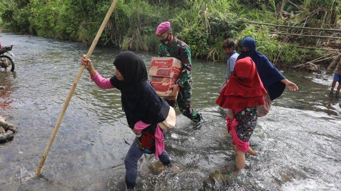 Sejumlah anak-anak melintasi sungai sambil membawa sembako di perbatasan Desa Ulumanda dan Desa Pompenga, Kecamatan Ulumanda, Kabupaten Majene, Sulbar, Jumat (22/1/2021).