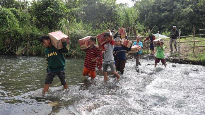 Sejumlah anak-anak melintasi sungai sambil membawa sembako di perbatasan Desa Ulumanda dan Desa Pompenga, Kecamatan Ulumanda, Kabupaten Majene, Sulbar, Jumat (22/1/2021).