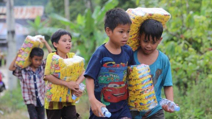 Sejumlah anak-anak melintasi sungai sambil membawa sembako di perbatasan Desa Ulumanda dan Desa Pompenga, Kecamatan Ulumanda, Kabupaten Majene, Sulbar, Jumat (22/1/2021).