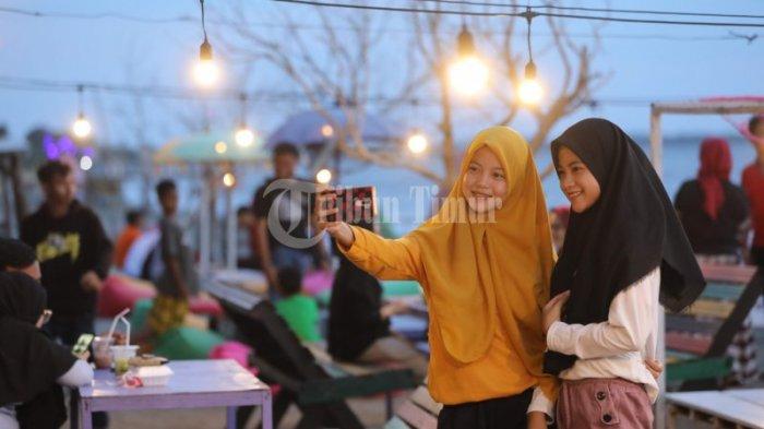 Sejumlah pengunjung berswafoto di The Old Sunset yang terletak di Pesisir Pantai Topejawa, Takalar, Sulawesi Selatan, Sabtu (25/7/2020) sore. Destinasi ini menyediakan berbagai spot foto untuk para pengunjung mulai dari pohon ranting yang sengaja tertanam menambah kesan eksotis hingga jembatan gantung untuk bisa melihat senja dari jarak lebih dekat.