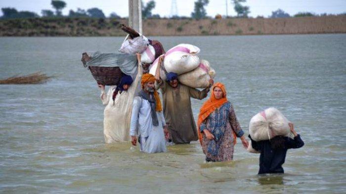 Satu keluarga berjalan menerobos banjir yang terjadi setelah hujan deras mengguyur Jaffarabad, sebuah distrik di Provinsi Baluchistan, Pakistan pada Rabu, 24 Agustus 2022. Hujan telah memicu terjadinya banjir bandang dan menyebabkan kerusakan di banyak wilayah Pakistan sejak Juni.