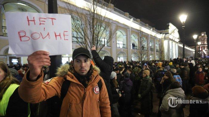 Seorang demonstran memegang plakat bertuliskan