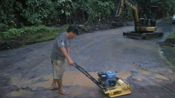 Seorang pekerja sedang memadatkan material pasir yang digunakan untuk memperbaiki jembatan Kembes yang hampir putus di Desa Kembes, Kecamatan Tombulu, Kabupaten Minahasa, Selasa (28/12/2021).