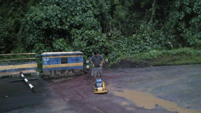 Seorang pekerja sedang memadatkan material pasir yang digunakan untuk memperbaiki jembatan Kembes yang hampir putus di Desa Kembes, Kecamatan Tombulu, Kabupaten Minahasa, Selasa (28/12/2021).