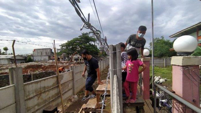 Dinding yang dibangun di depan gedung milik Asep memaksa keluarganya keluar rumah menggunakan tangga dan kursi.