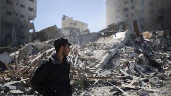 Seorang polisi Palestina berdiri di depan reruntuhan Jala Tower, gedung 13 lantai kantor media Al Jazeera dan Associated Press, yang diledakkan serangan udara Israel di Gaza pada Sabtu (15/5/2021).