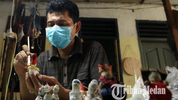 Faisal Walad menyelesaikan kerajinan miniatur boneka berpakaian adat multi etnis berbahan koran bekas di Galeri J-ART, di Jalan Umar, Medan, Selasa (16/2/2021). Kerajinan tersebut guna melestarikan sekaligus mempromosikan tujuh pakaian adat di Sumatera Utara, dijual dengan harga Rp 150.000 per pasang.