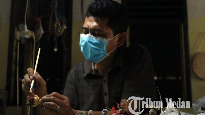 Faisal Walad menyelesaikan kerajinan miniatur boneka berpakaian adat multi etnis berbahan koran bekas di Galeri J-ART, di Jalan Umar, Medan, Selasa (16/2/2021). Kerajinan tersebut guna melestarikan sekaligus mempromosikan tujuh pakaian adat di Sumatera Utara, dijual dengan harga Rp 150.000 per pasang.
