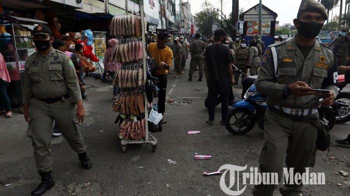 Petugas Satpol PP menertibkan pedagang kaki lima (PKL) yang berdagang di pedestrian di Jalan Gatot Subroto, Medan, Kamis (18/2/2021). Selain menertibkan, petugas juga menyosialisasikan warga agar tetap mematuhi protokol kesehatan ditengah pandemi Covid-19.