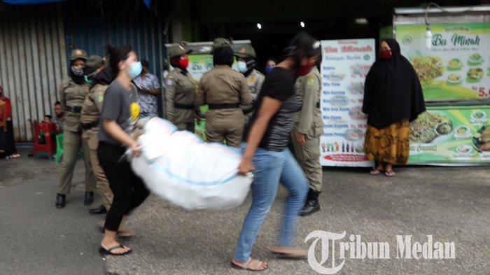 Petugas Satpol PP menertibkan pedagang kaki lima (PKL) yang berdagang di pedestrian di Jalan Gatot Subroto, Medan, Kamis (18/2/2021). Selain menertibkan, petugas juga menyosialisasikan warga agar tetap mematuhi protokol kesehatan ditengah pandemi Covid-19.