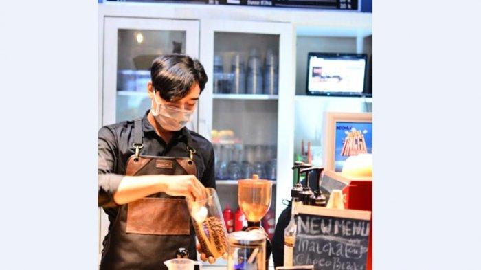 SEORANG pelayan sedang mempersiapkan kopi pesanan pengunjung.