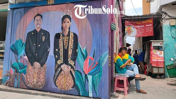 Warga sedang menikmati makan siang di sebelah Mural Kaesang-Erina yang dilukis pada sebuah toko di Jalan Gatot Subroto, Solo, Selasa (20/9/2022).