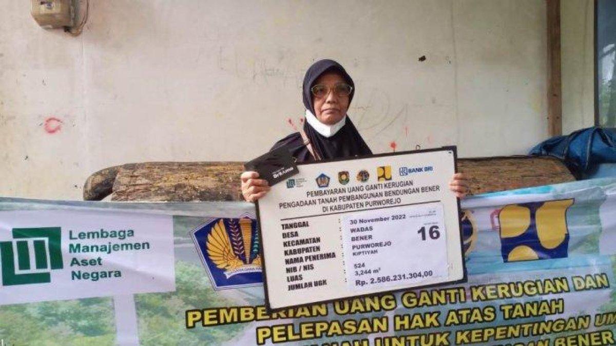 Senyum Kiptiyah (jilbab hitam) merekah, saat menerima 6 buku rekening. Kiptiyah adalah warga Desa Wadas yang mendapat nominal UGK tertinggi dengan total Rp11 miliar pada acara pembayaran UGK proyek Bendungan Bener di Balai Desa Wadas, Rabu (30/11/2022) siang.
