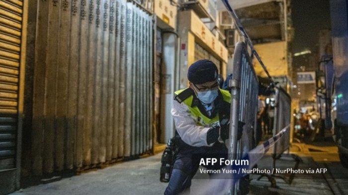 Seorang polisi memasang barikade di lorong lorong permukiman Hongkong menyusul diberlakukannya lockdown selama 2 hari.