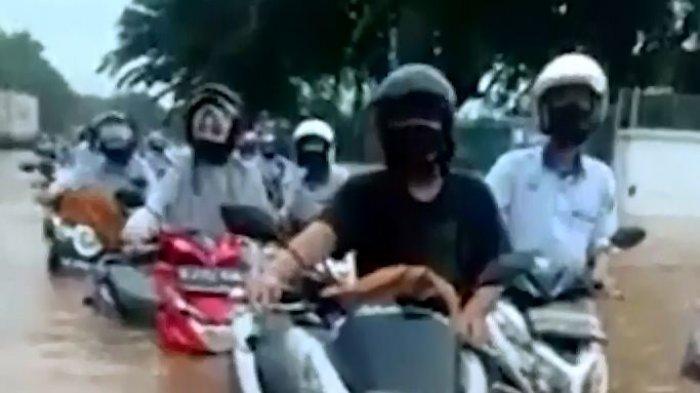 Para pekerja pabrik terlihat sedang mendorong motor karena banjir mencapai sepinggang orang dewasa