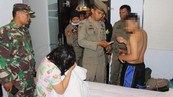 Petugas Satpol PP memeriksa identitas sepasang remaja yang ditemukan di sebuah kamar hotel di Padang, Minggu (3/11) dinihari.