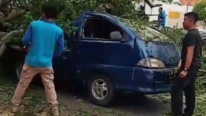 Warga memotong pohon tumbang yang menimpa 1 unit kendaraan di Padang Sumatera Barat, Jumat (2/4/2021).