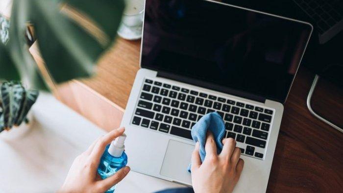 Ilustrasi membersihkan laptop dengan kain mikrofiber.