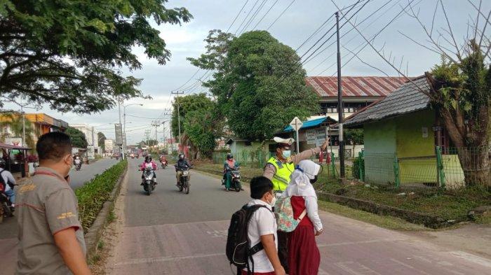 Personel Polres Melawi saat membantu menyeberangkan pelajar, Selasa 23 Februari 2021