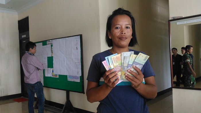 Siti Maryam menunjukkan uang baru tahun emisi 2016 usai melakukan penukaran di Mobil Kas Keliling Bank Indonesia, di Entikong, Rabu (11/1/2017).