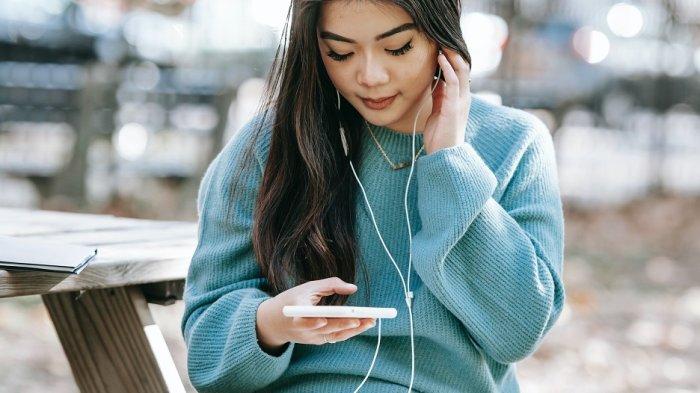 Ilustrasi seorang wanita menggunakan earphone untuk mendengarkan musik