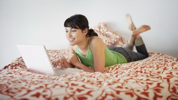 Ilustarasi menggunakan laptop di atas kasur yang bisa berakibat buruk untuk laptop
