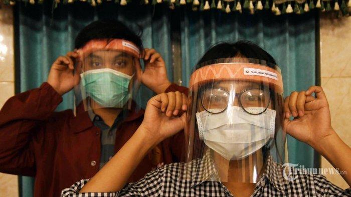 FACE SHIELD SEDERHANA - Dua mahasiswa mencoba face shield sederhana buatan mahasiswa Fakultas Kedokteran Universitas Airlangga di sela tugas kuliah onlinenya di aula FK Unair, Senin (23/3/2020).