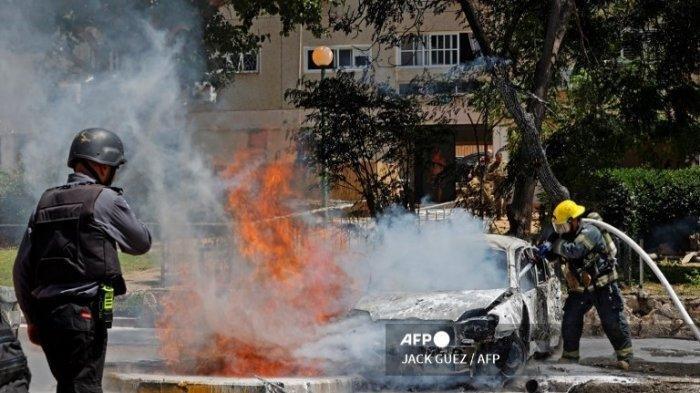 Seorang petugas pemadam kebakaran memadamkan kendaraan yang terbakar setelah roket diluncurkan dari Jalur Gaza, yang dikendalikan oleh gerakan Hamas Palestina, mendarat di kota Ashkelon di Israel selatan pada 11 Mei 2021. Israel dan Hamas saling baku tembak, dalam eskalasi dramatis antara yang pahit musuh yang dipicu oleh kerusuhan di titik nyala kompleks Masjid Al-Aqsa di Yerusalem.