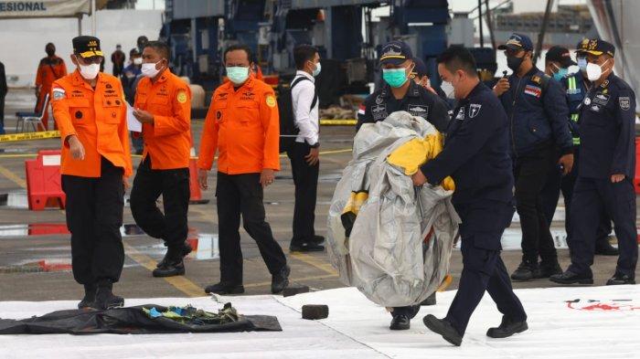 Petugas memeriksa benda yang diduga serpihan dari pesawat Sriwijaya Air SJ 182 rute Jakarta - Pontianak yang hilang kontak di perairan Pulau Seribu, di Dermaga JICT, Jakarta, Minggu (10/1/2021). Pesawat Sriwijaya Air SJ 182 yang hilang kontak pada Sabtu (9/1) sekitar pukul 14.40 WIB di ketinggian 10 ribu kaki tersebut membawa enam awak dan 56 penumpang.